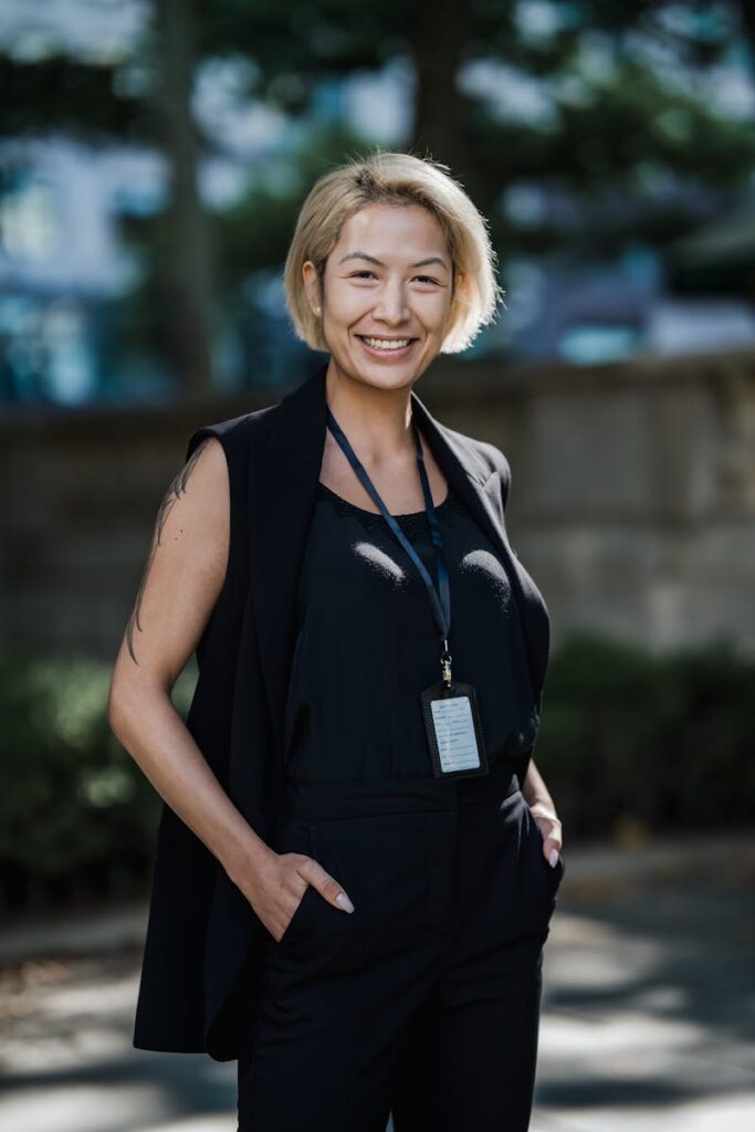 Confident professional woman smiling in an outdoor setting, wearing formal attire.